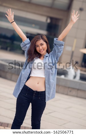 Vertical portrait of a happy youngster standing with hands up