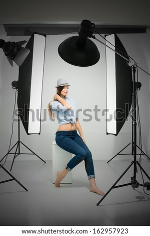 Vertical portrait of a young lady in hat working in the studio as a model