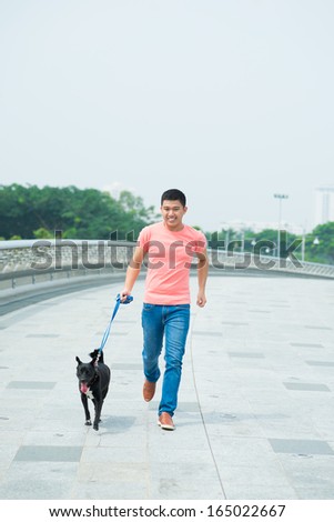 Image of a young man walking with his dog outside