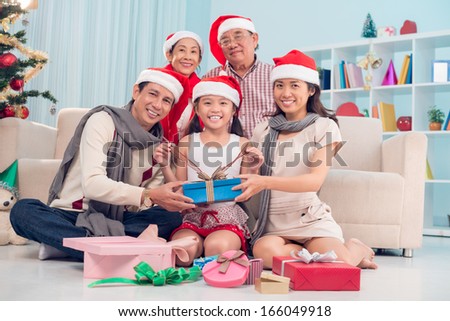 Image of a big family in Santa hat with Christmas presents sitting on the floor and looking at camera
