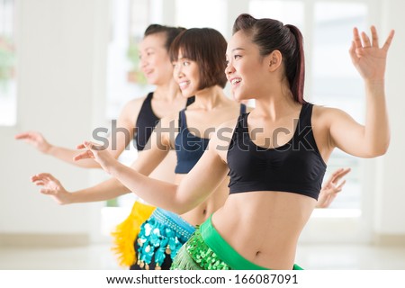Young women performing belly dance in a dance studio on the foreground