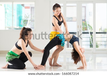 Image of a young dancer doing pilate while her instructor and friend helping in the studio