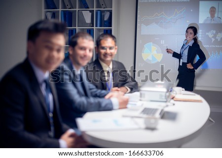 Portrait of a young business lady presenting the company\'s strategy on the foreground, the colleague is on Skype on the foreground