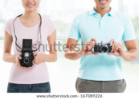 Cropped image of a young couple with old-styled photo cameras
