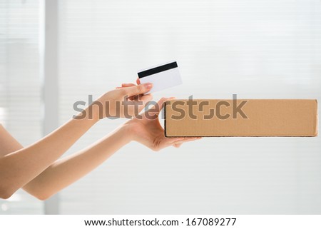 Cropped image of human hands holding a parcel and a credit card