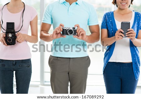 Cropped image of young people with old fashioned cameras and a modern smartphone
