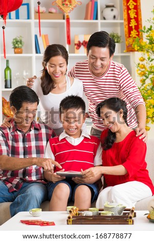 Vertical image of a big family presented a boy with a New Year present at home