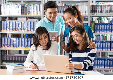 Four students studying together in library
