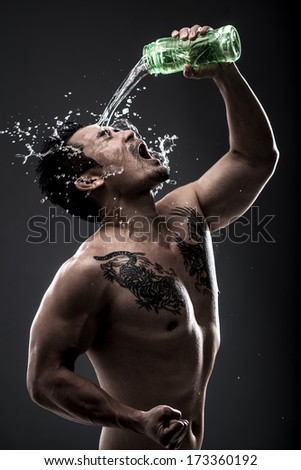 Vertical image of a masculine man pouring water over himself