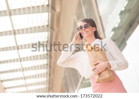 Angle view of a young lady with a shopping bag talking by phone
