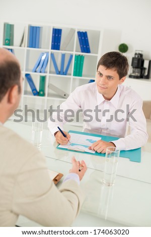 Vertical image of an employee discussing the company\'??s strategy tet-a-tet with his boss on the foreground