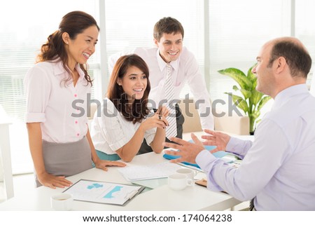 Image of a company staff consulting with her boss about some working moments at the office on the foreground