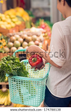 Back view of a woman in the grocery shop on the foreground