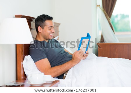 Copy-spaced image of a man holding a photo frame and smiling while lying in the bed