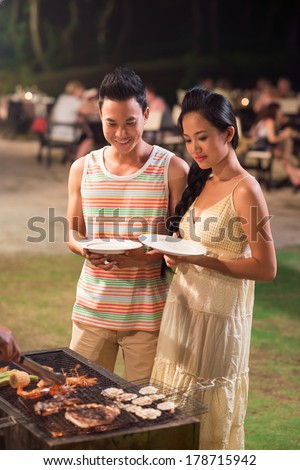 Vertical image of a young couple waiting while their tasty dinner will be ready on the foreground