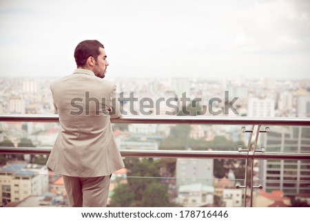 Back view of a peaceful businessman standing and looking at the urban view