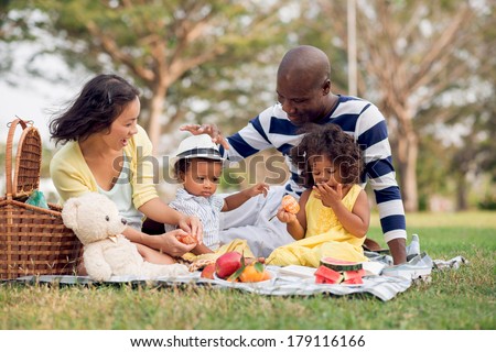 Image of a mixed family having fun while picnicking in the park