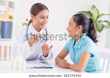 Image of a physician making a prescription for a senior patient on the foreground
