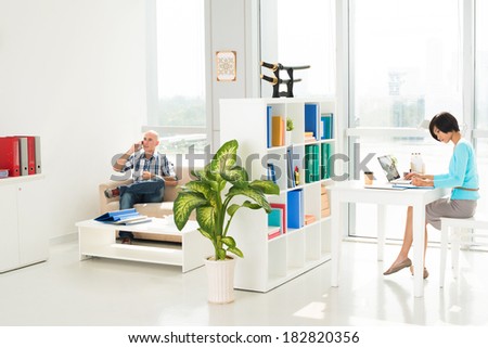 Businesspeople working in their own part of office, woman networking while man talking by phone