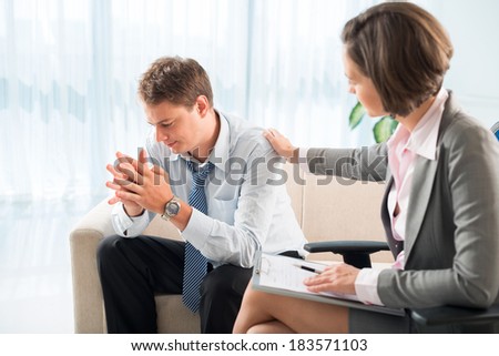 Psychologist comforting depressed businessman at session
