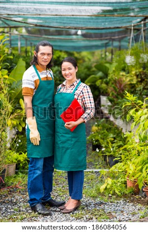 Happy Asian woman and man looking at camera in the greenhouse