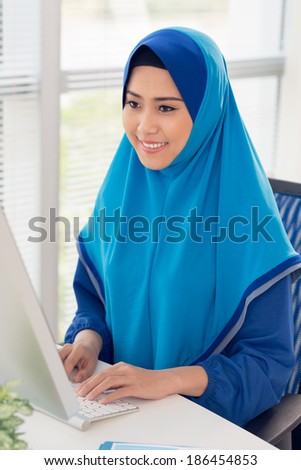 Vietnamese Muslim woman working on computer in the office