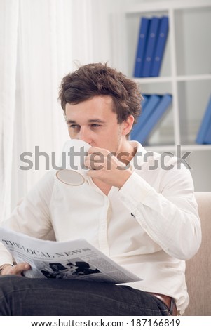 Handsome man reading newspaper and drinking coffee