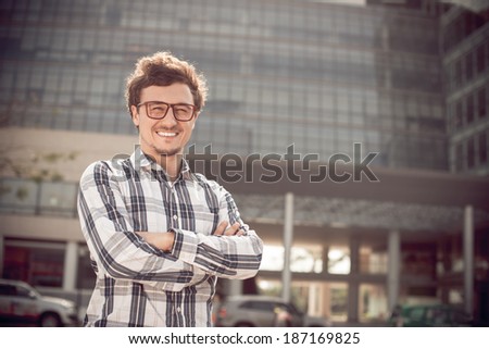 Man in glasses standing on the street in front of high building