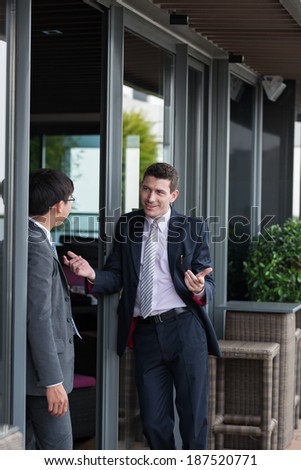 Businessman explaining something to his colleague, standing near building entrance