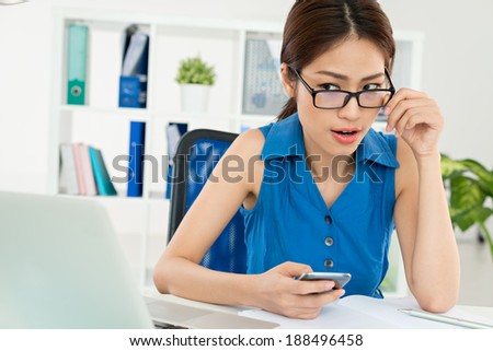 Asian manager dialing a number looking at the screen of her laptop