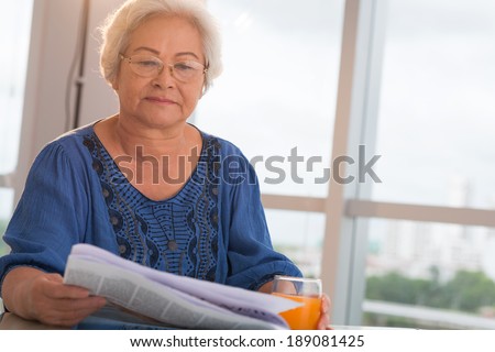 Mature Asian woman reading newspaper