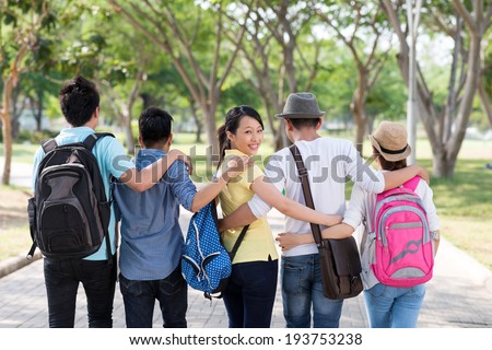 Asian students walking in the park together, view from the back