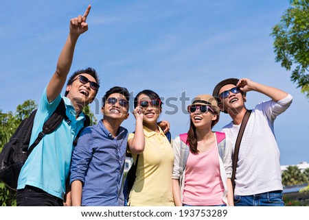 Asian guy showing something in the sky to his friends