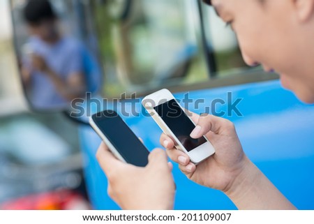 Close-up of boy holding two different smartphones and deciding which one to choose