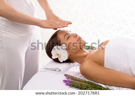 Masseur holding her hands over the head of the client to concentrate some energy