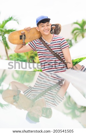 Young man with a skateboard on the back of his shoulders