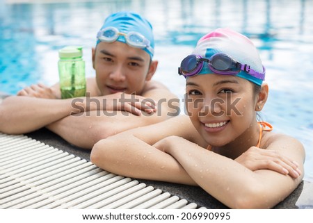 Smiling Vietnamese couple resting in the swimming pool