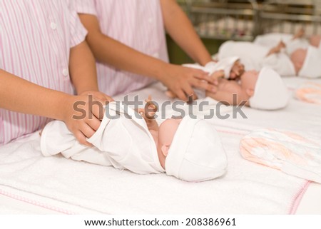 Hands dressing the baby dolls
