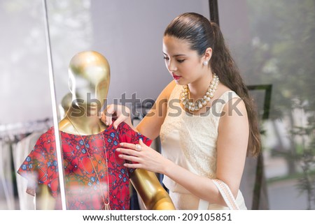 Beautiful brunette touching dress on the mannequin
