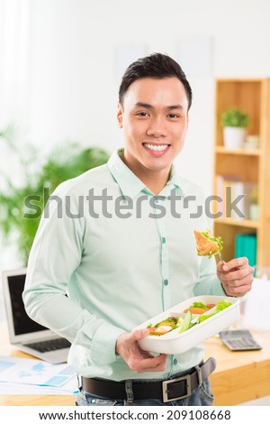 Portrait of Vietnamese young man eating salad from the container