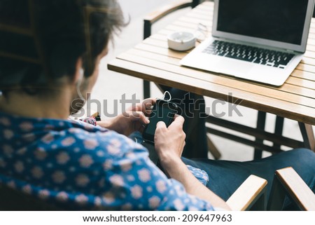 Young man texting while sitting in the cafe selective focus Young man texting while sitting in the cafe selective focus