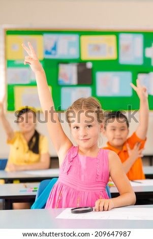 Schoolgirl raising hand and showing two fingers at a lesson