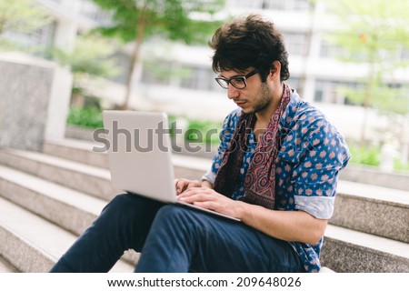Hipster blogging while sitting on the steps outdoors Hipster blogging while sitting on the steps outdoors