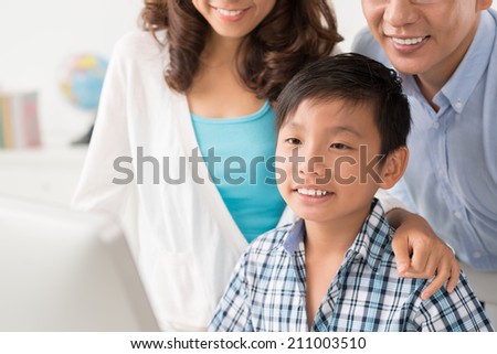 Cropped image of boy and his parents gathered in front of computer monitor