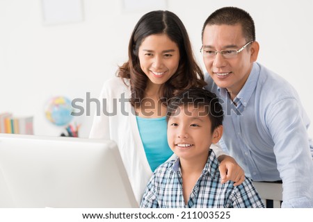 Happy Vietnamese family looking at the computer monitor