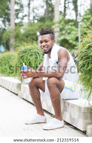 Happy African-American sportsman resting after exhausting training outdoors