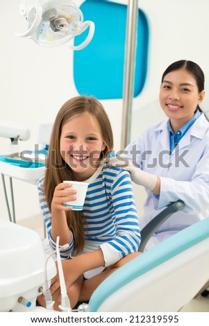 Portrait of girl with a glass of water and her doctor before teeth examination