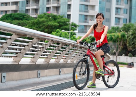 Portrait of smiling Asian woman listening to the music and riding on bike