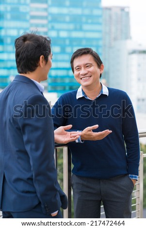 Asian business people chatting outdoors during the break