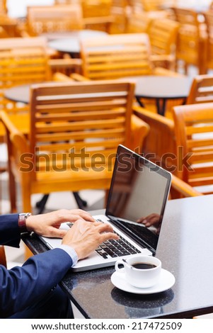 Hands of businessman working on laptop in the cafe